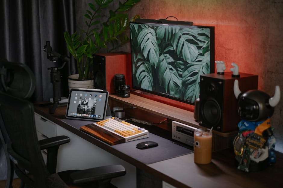 A stylish home office setup featuring a monitor, tablet, speakers, and decorative items